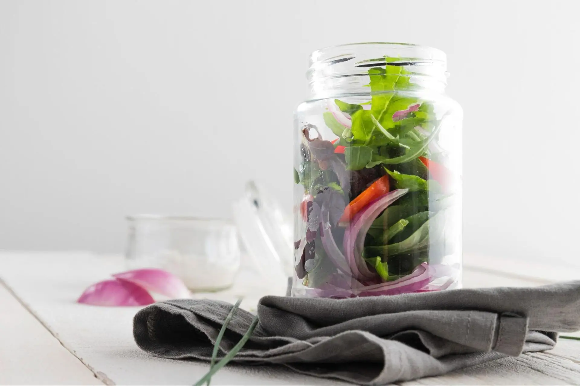 Close up of a fresh leafy salad in a glass jar.