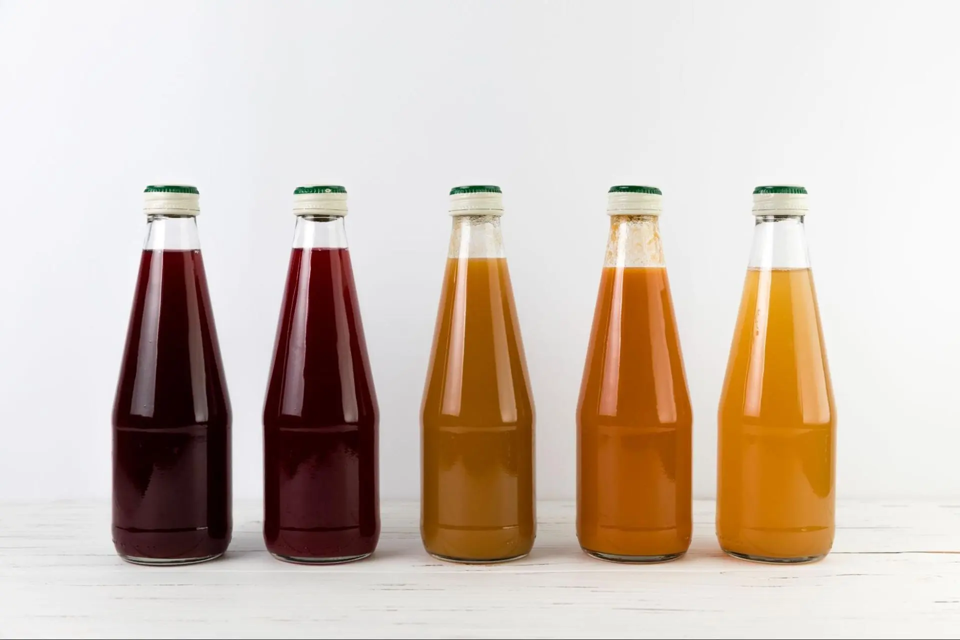 Juices in sustainable glass bottles on a table with white background.