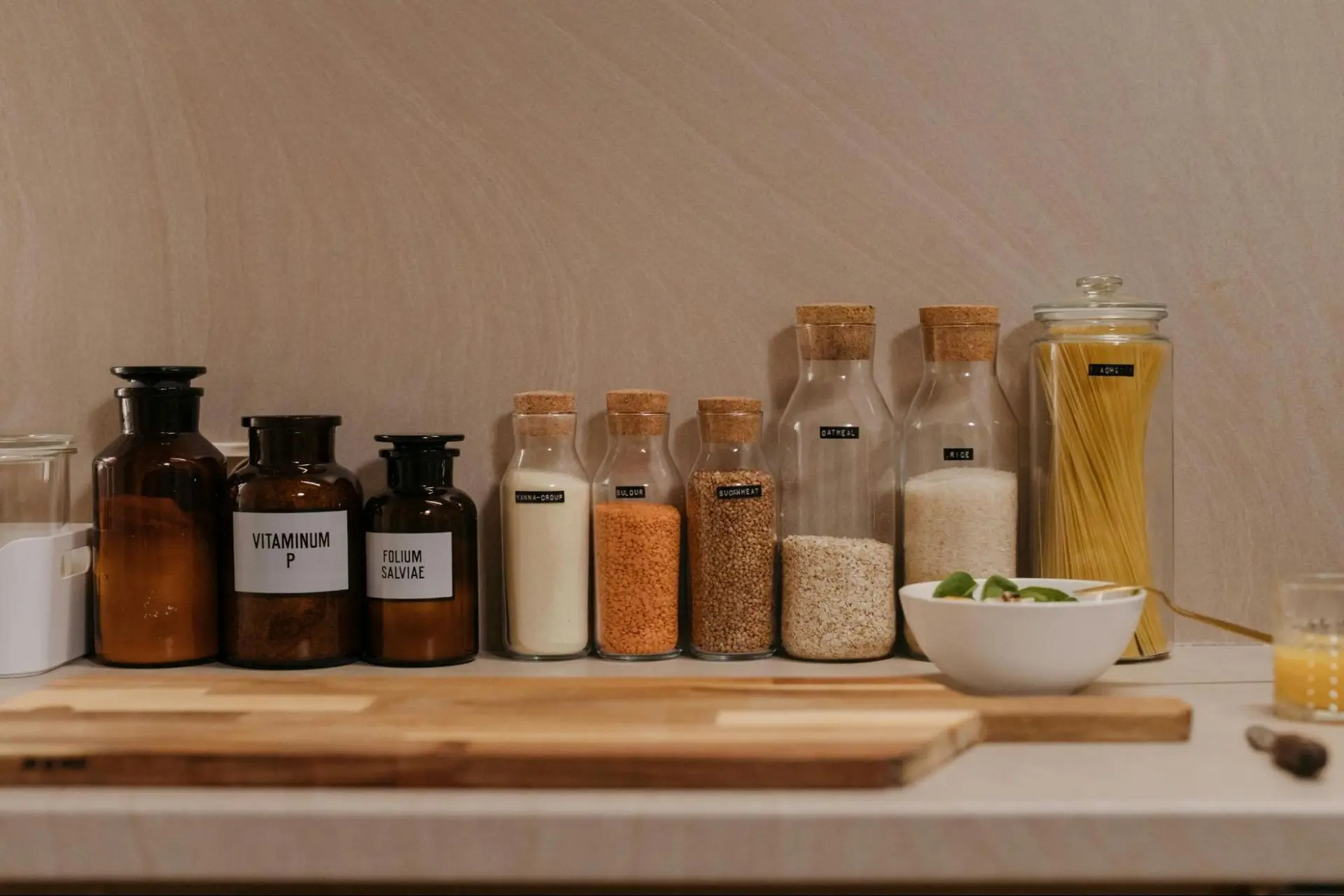 Glass bottles with seeds and pasta on a kitchen counter.
