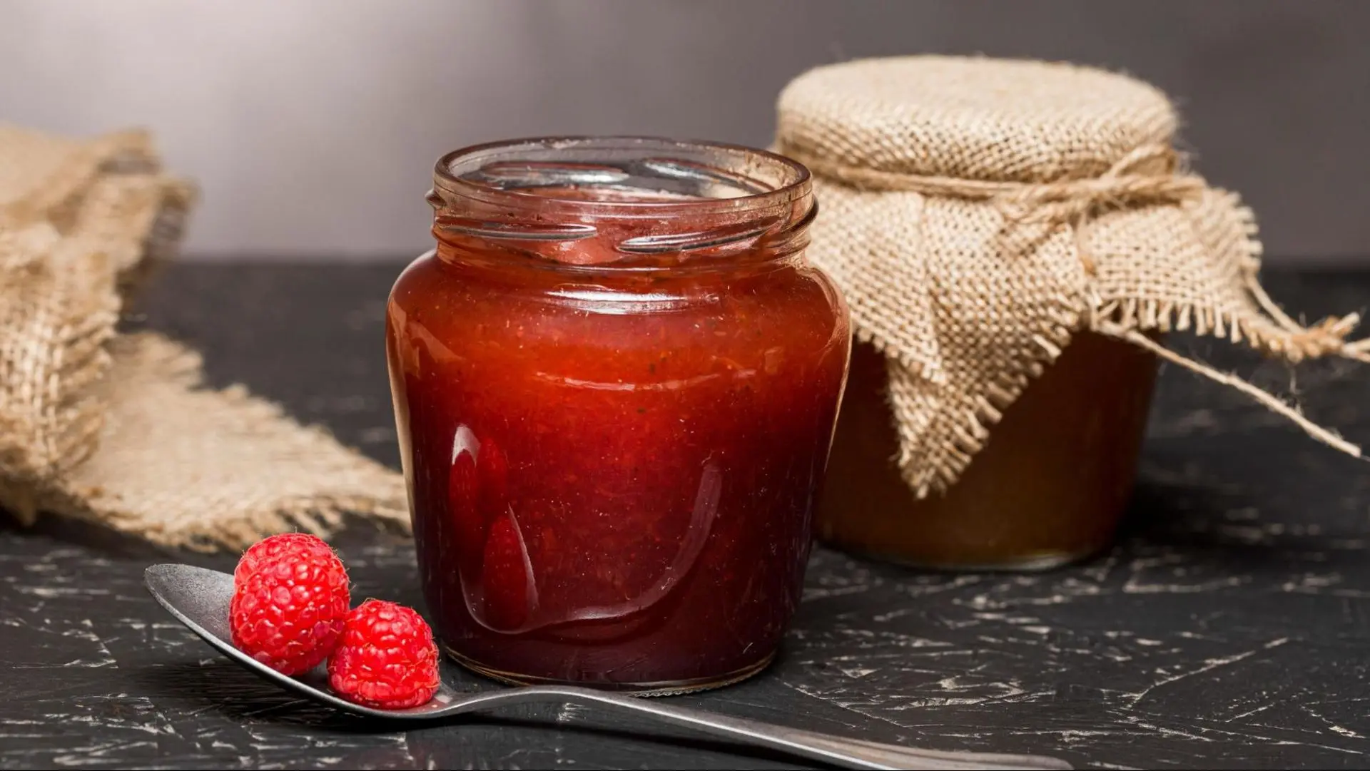 Close up of a raspberry jam in an eco-friendly glass jar.